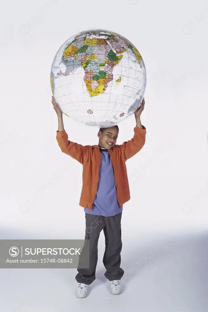 Portrait of a boy holding an inflatable globe on top of his head