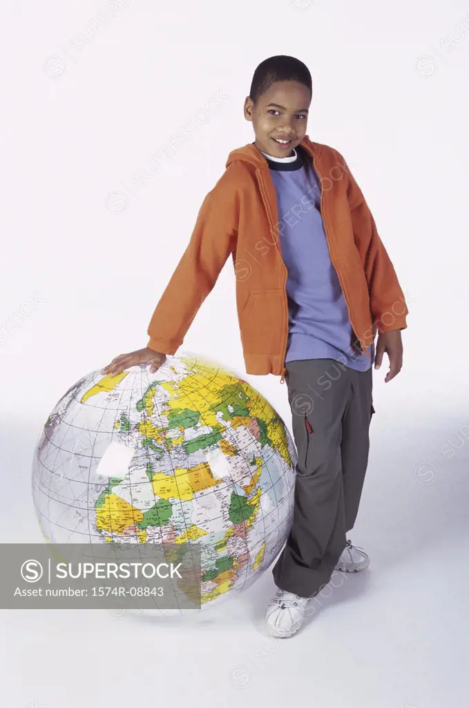 Portrait of a boy standing leaning against an inflatable globe