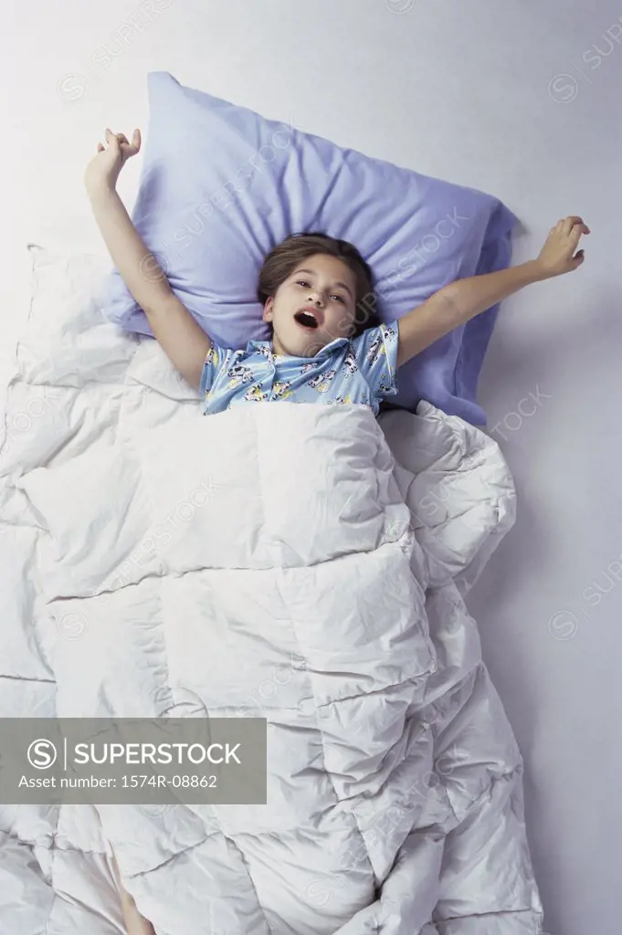High angle view of a girl lying in bed yawning