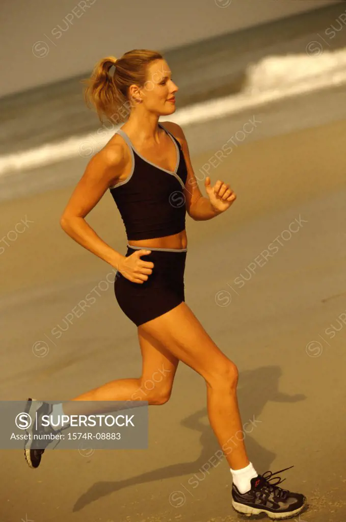 Side profile of a young woman running on the beach