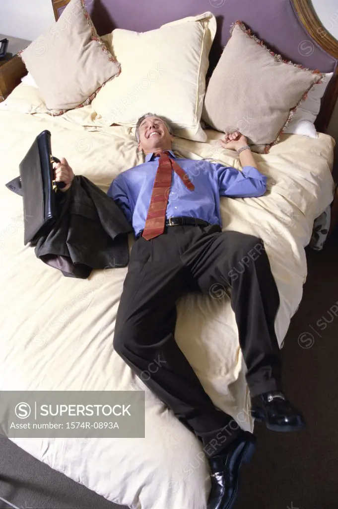 High angle view of a businessman lying on a bed in a hotel room