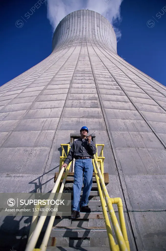 Low angle view of a man standing on a staircase of a smoke stack at a power plant
