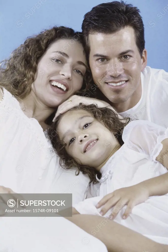 Portrait of parents and their daughter lying in bed together