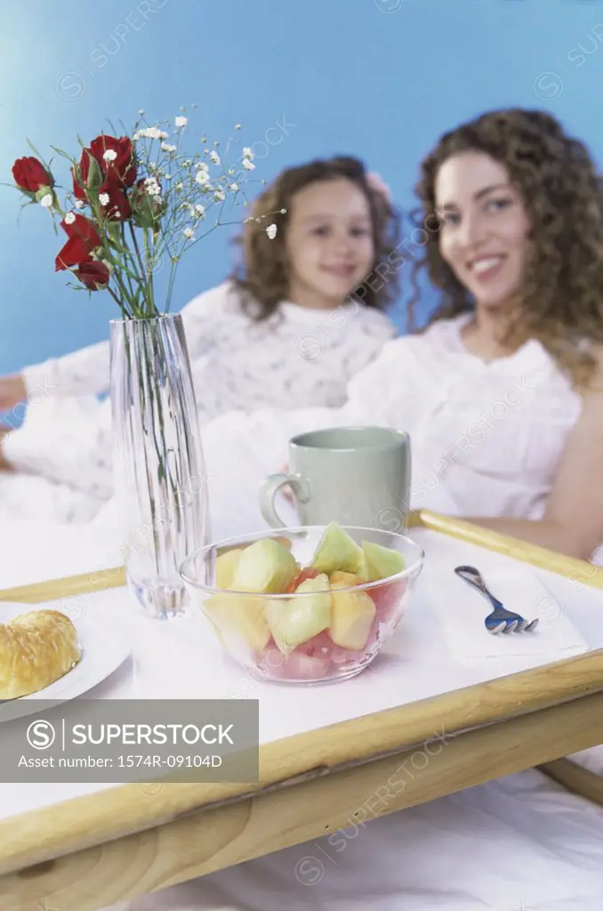 Portrait of a mother and daughter in bed together with a breakfast tray