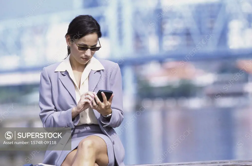 Young businesswoman sitting outdoors operating a hand held device