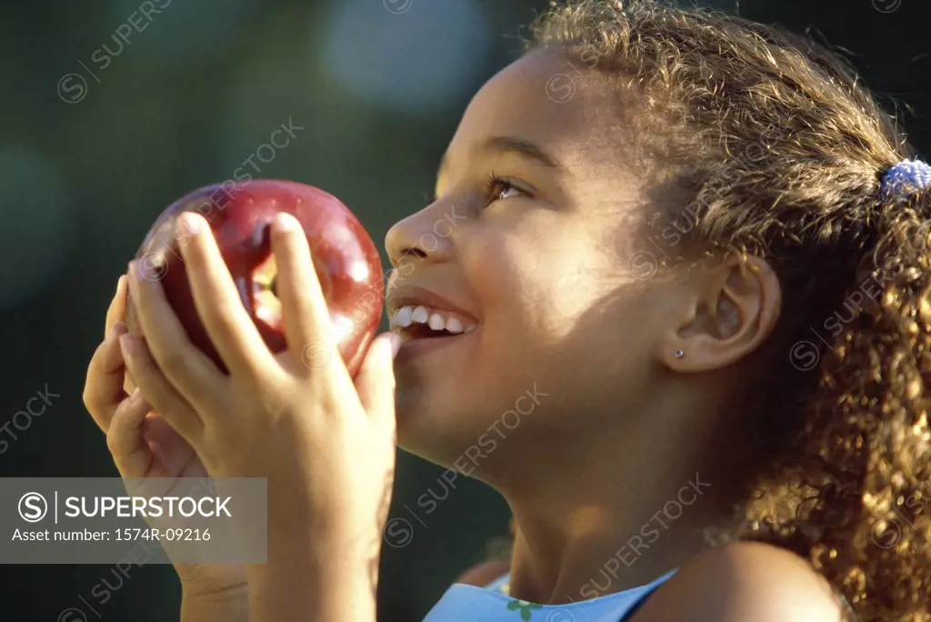 Side profile of a girl holding an apple