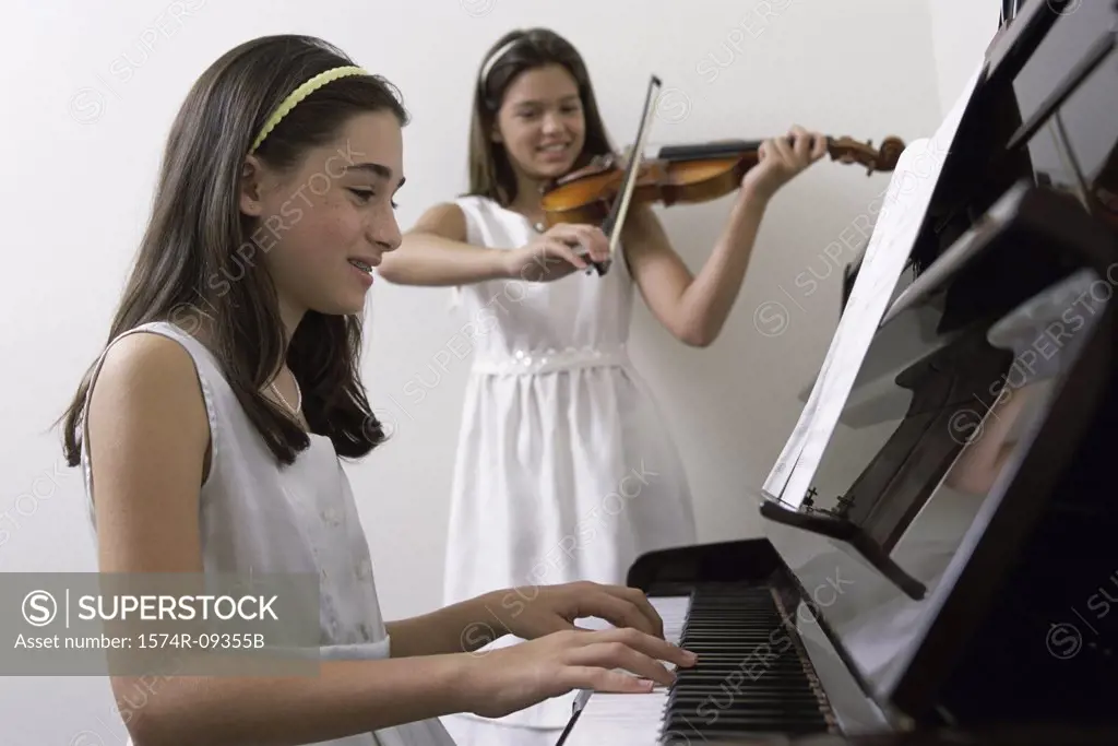 Girl playing the piano and another playing the violin