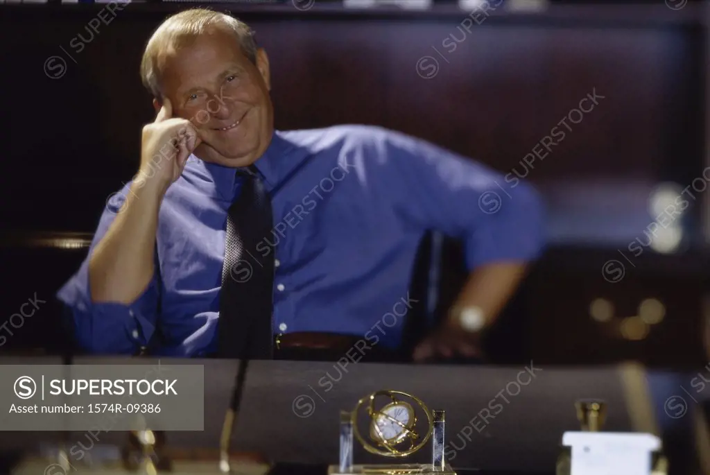 Portrait of a businessman seated behind an office desk smiling