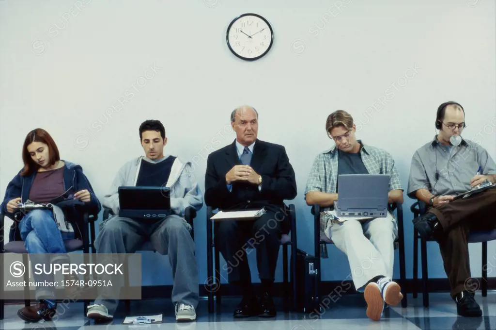 Business executives sitting in a row operating laptops