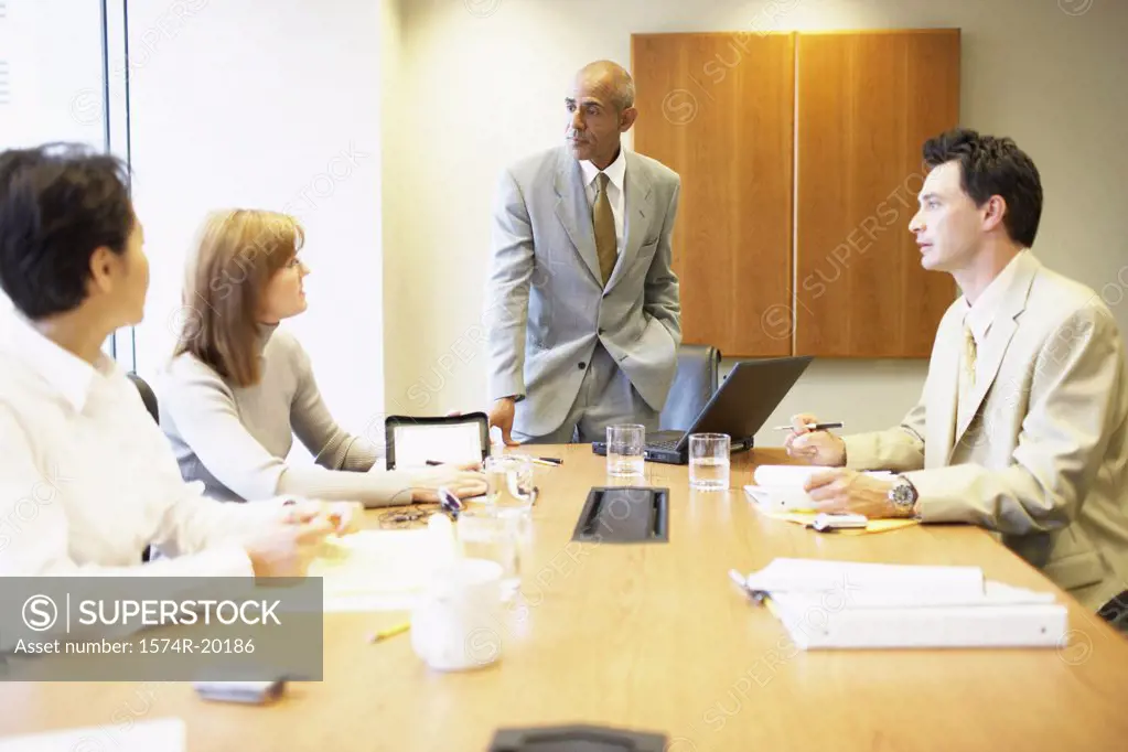 Two businessmen and two businesswomen talking in a conference room