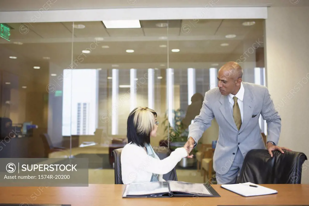 Businessman and a businesswoman shaking hands in an office