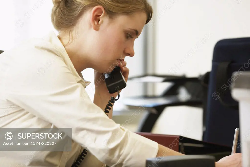 Side profile of a businesswoman using a telephone in an office