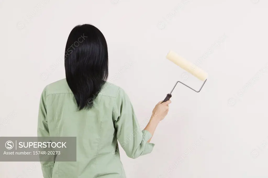 Rear view of a woman holding a paint roller