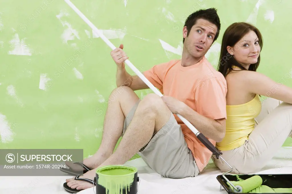 Portrait of a young couple sitting back to back on a drop sheet