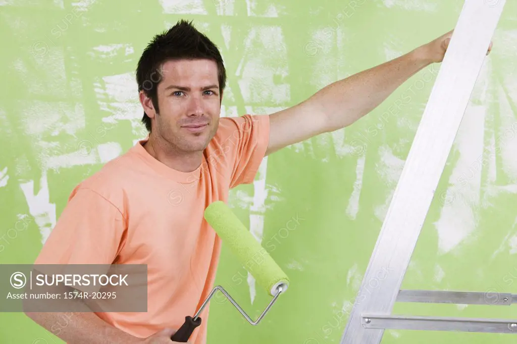Portrait of a young man holding a paint roller