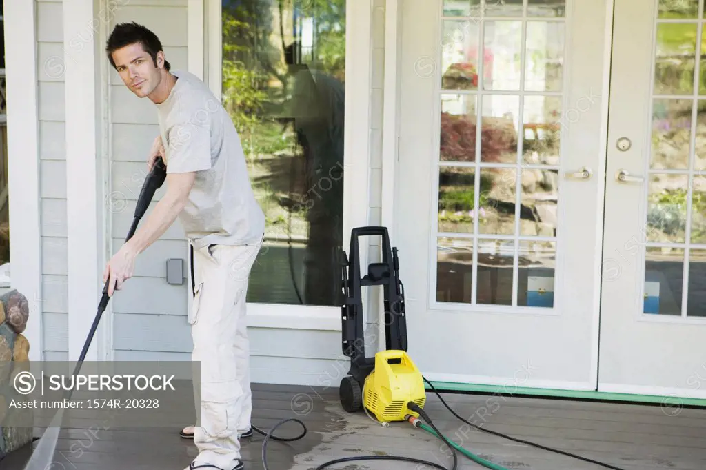 Portrait of a young man cleaning the porch of his house