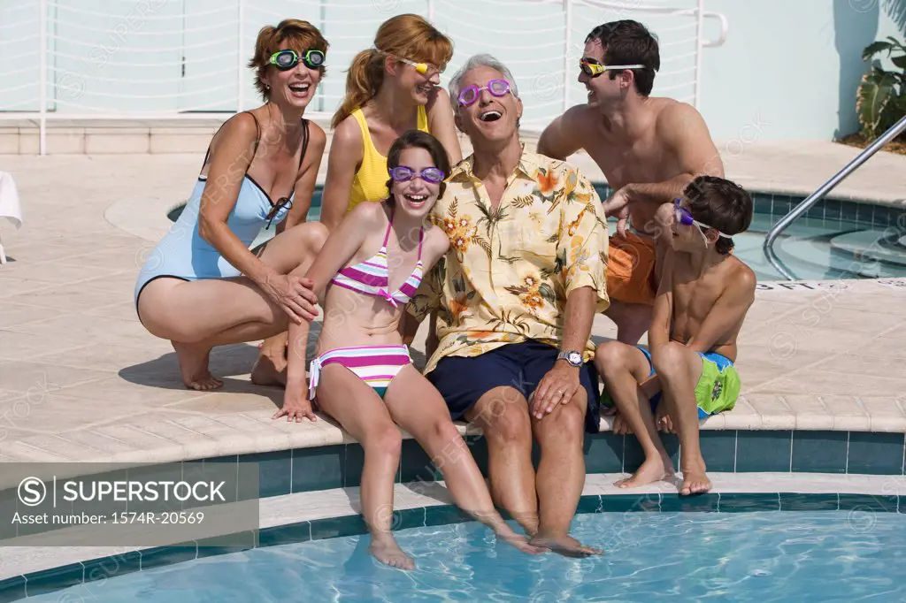 Family sitting at poolside and smiling