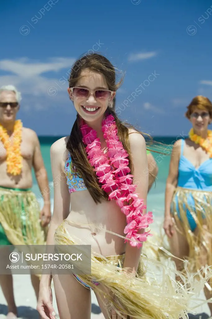 Close-up of a girl smiling on the beach with her grandparents standing in the background