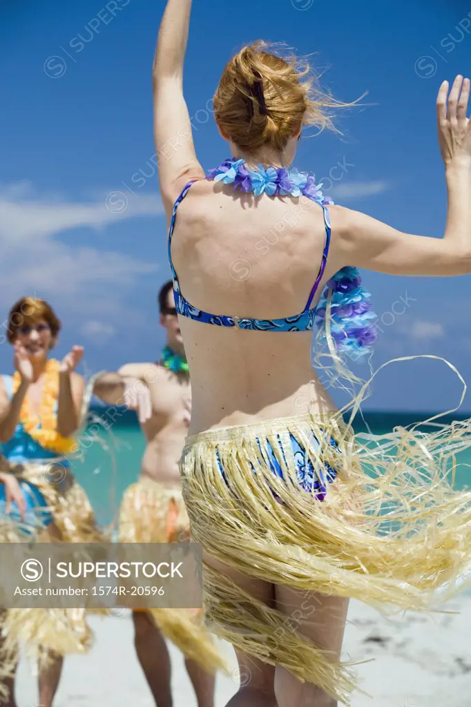Rear view of a young woman hula dancing on the beach