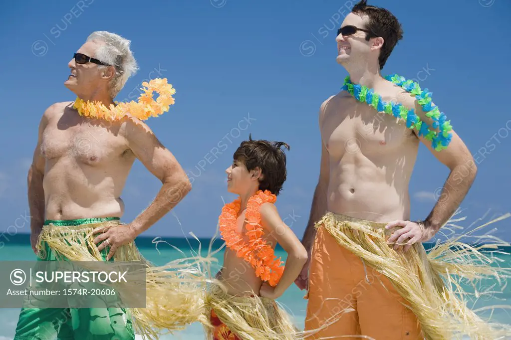 Side profile of a boy standing with his father and grandfather on the beach