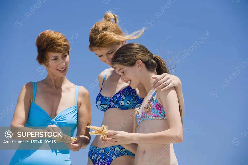 Side profile of a girl standing with her mother and grandmother looking at starfish