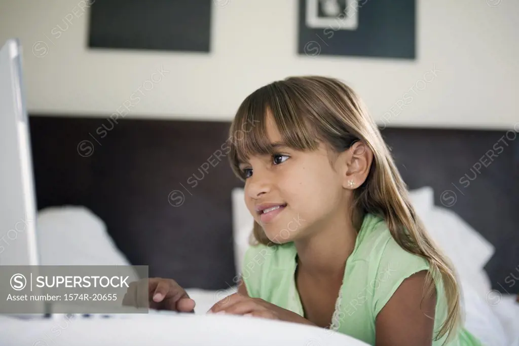 Close-up of a girl lying in the bed and using a laptop