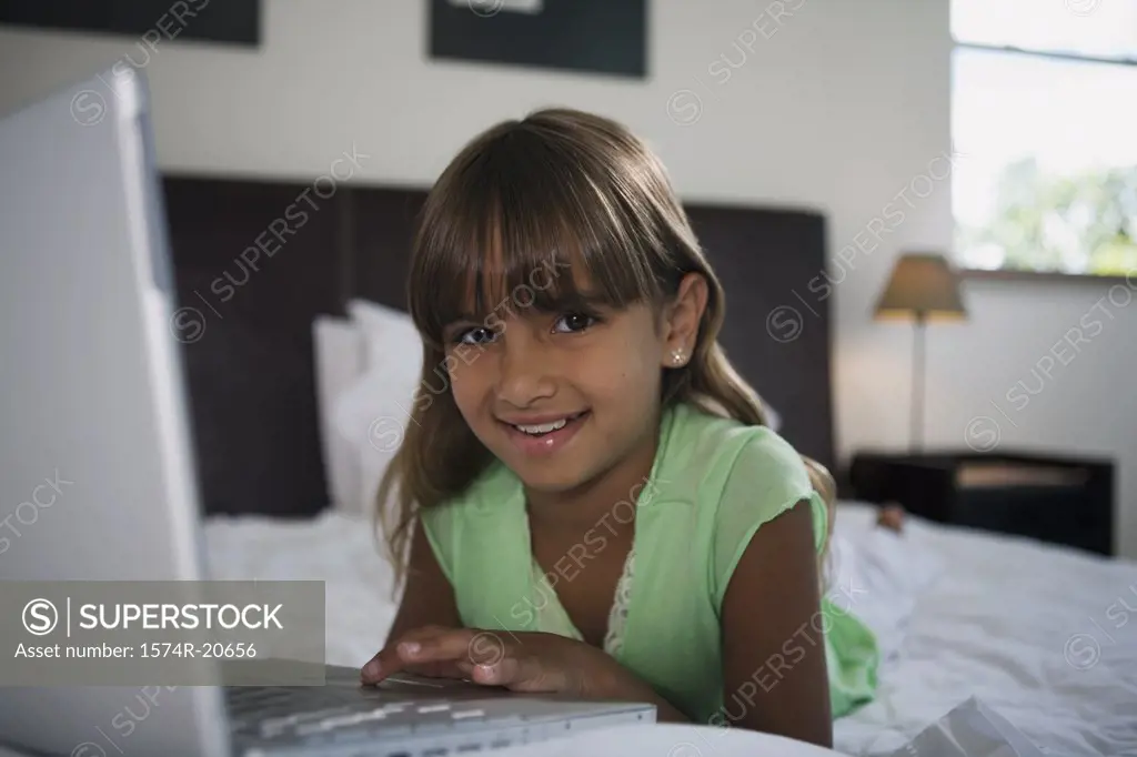 Portrait of a girl lying in the bed and using a laptop
