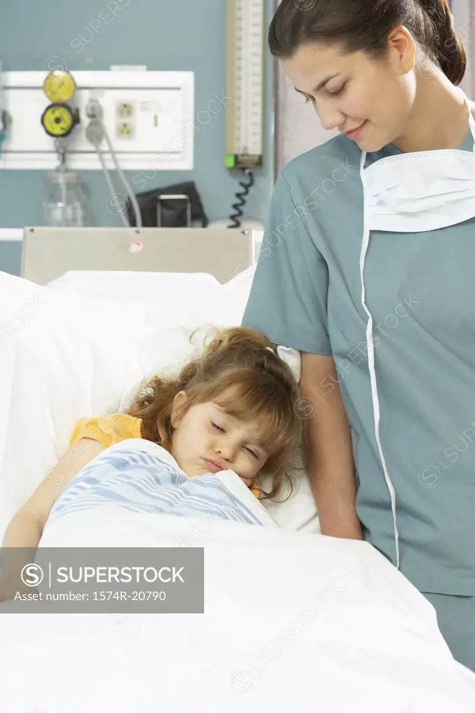 Girl sleeping on the bed and a female nurse standing beside her