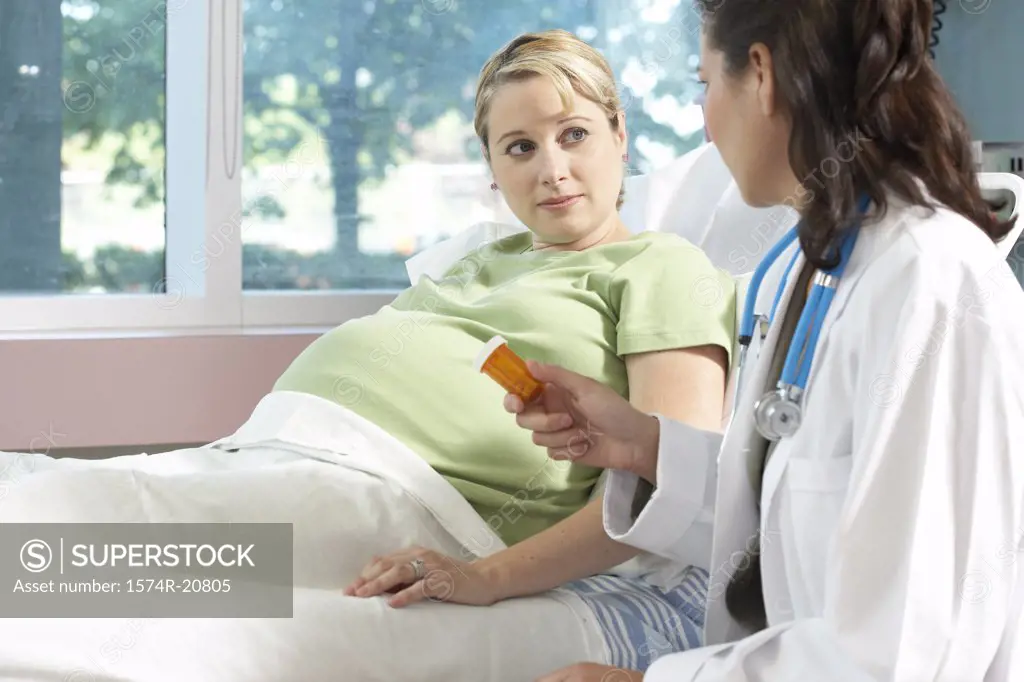Side profile of a female doctor giving a bottle of pills to a pregnant woman