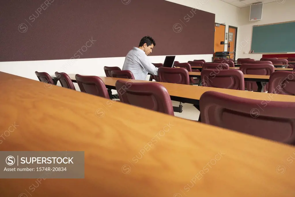 Side profile of a college student sitting in a lecture hall and using a laptop