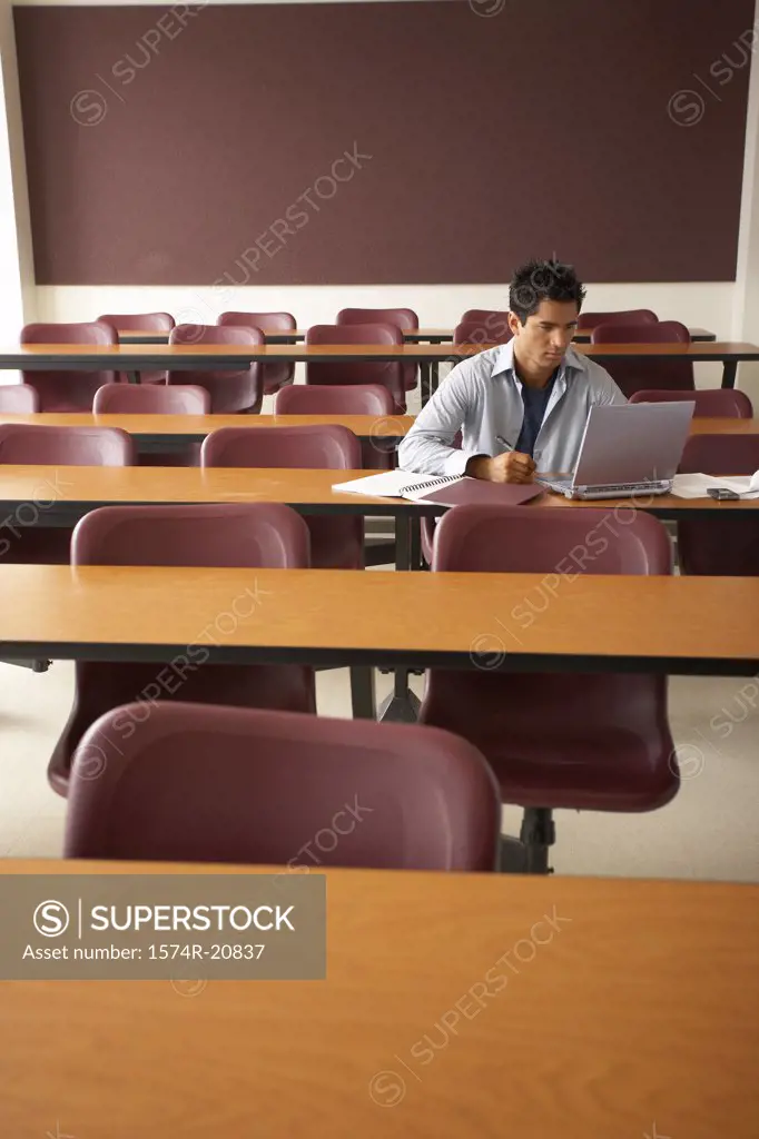 College student sitting in a lecture hall and using a laptop