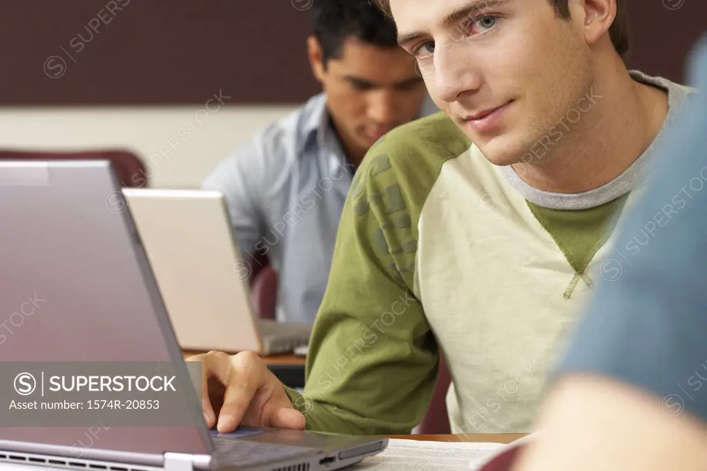 Two college students sitting in a lecture hall and using laptops