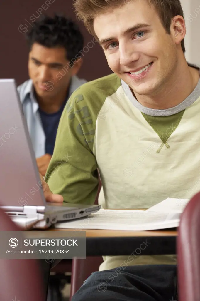 Two college students sitting in a lecture hall and using laptops