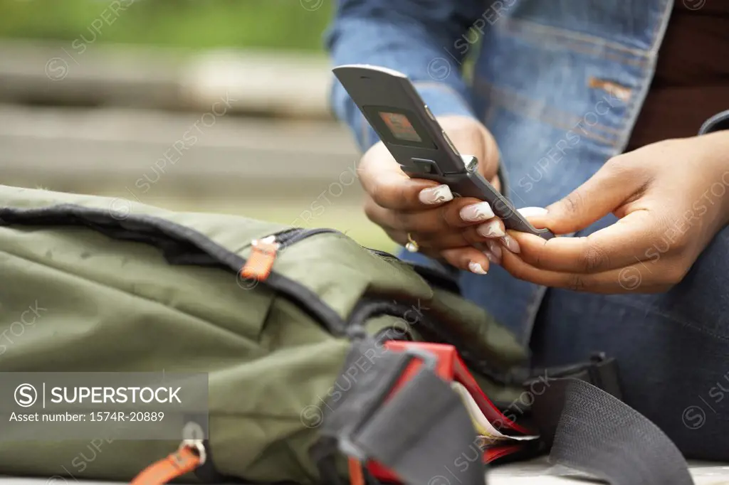 Mid section view of a college student using a mobile phone