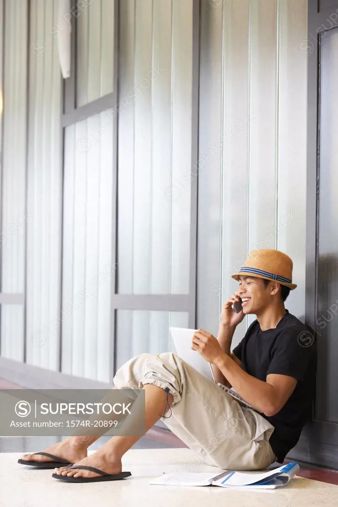 Side profile of a college student sitting in a corridor and talking on a mobile phone
