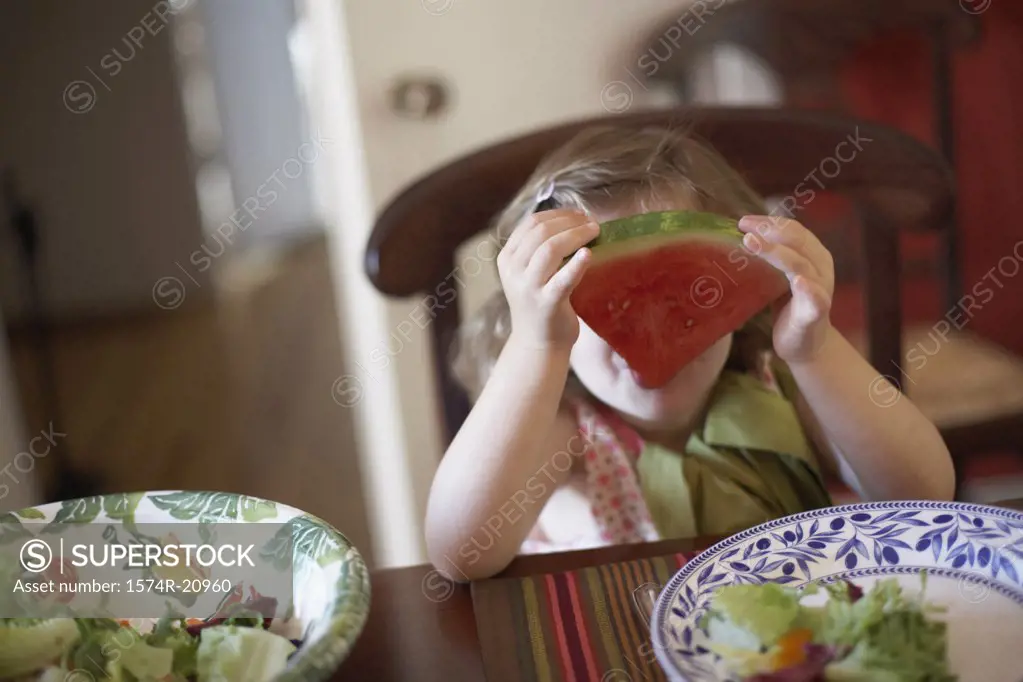 Close-up of a girl holding a slice of watermelon in front of her face