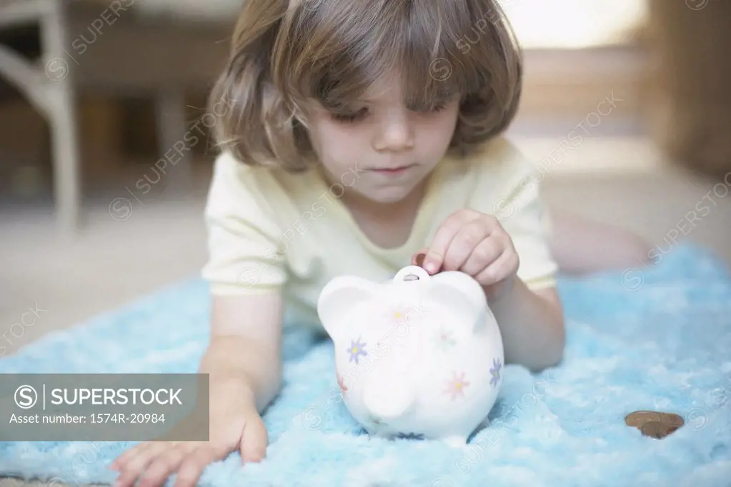 Close-up of a girl inserting a coin into a piggy bank