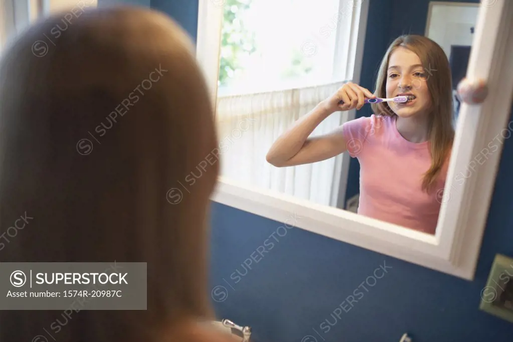 Reflection of a teenage girl brushing her teeth in a mirror
