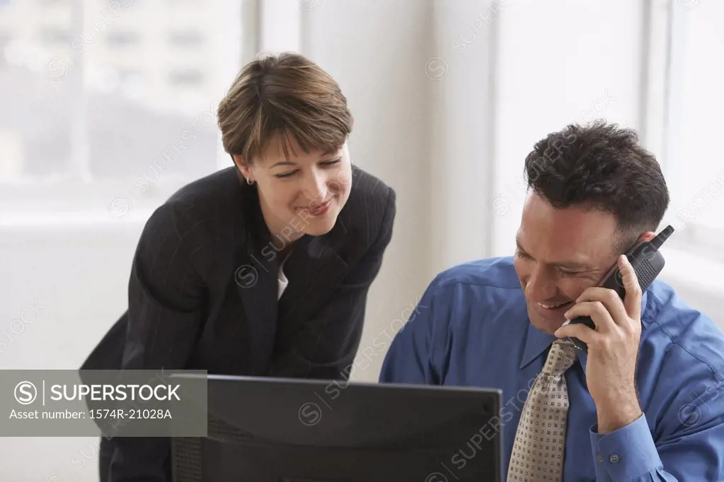 Close-up of a businessman talking on the phone with a businesswoman standing beside him