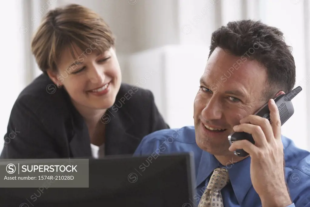 Businessman talking on the phone with a businesswoman standing beside him