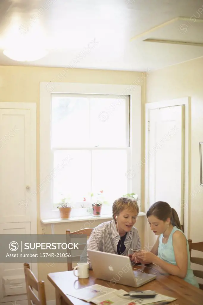 High angle view of a teenage girl and her grandmother looking at an MP3 player