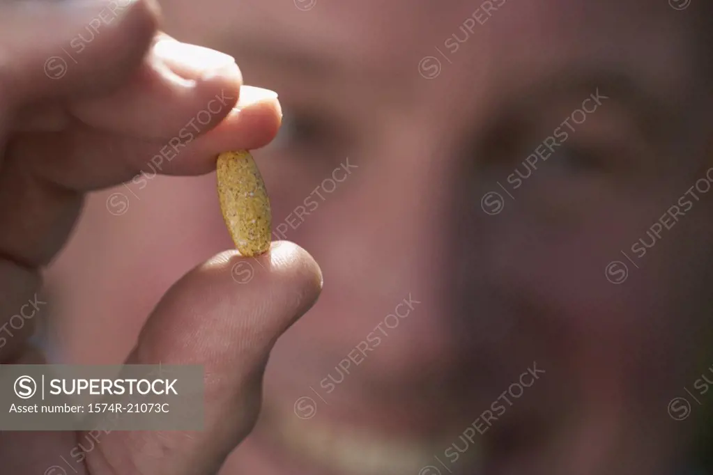 Close-up of a mature man showing a pill