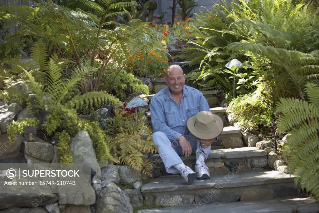 Mature man sitting on steps in a garden