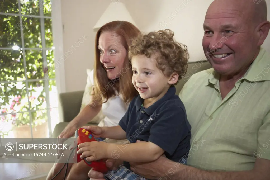 Close-up of a boy sitting with his grandparents and playing a video game