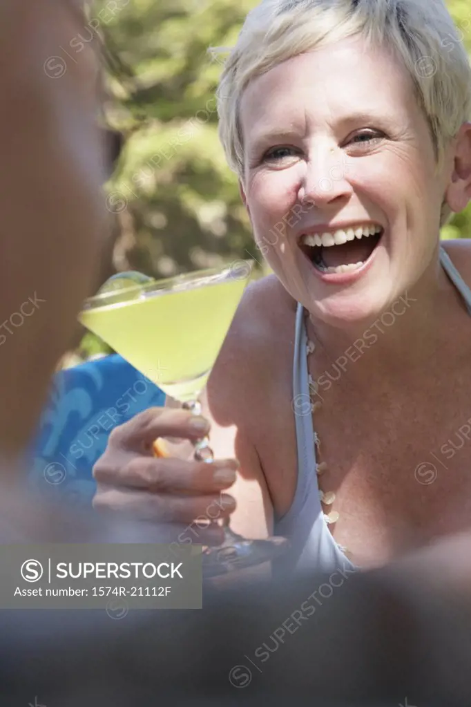 Close-up of a mature woman holding a martini and looking at a mature man