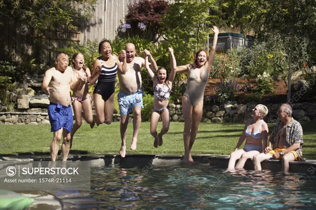 Group of people holding each other's hand and jumping into a swimming pool