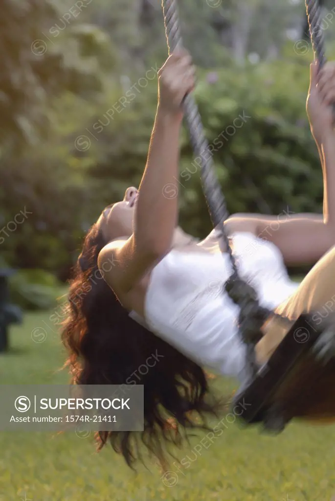 Young woman swinging on a rope swing