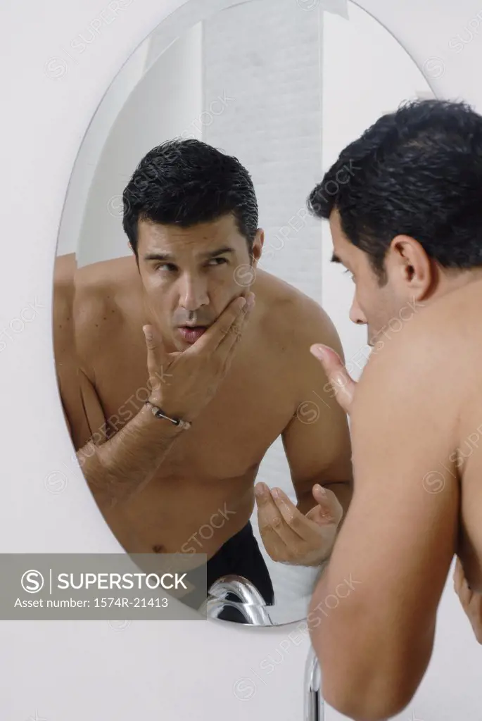 Mid adult man looking at himself in a mirror in the bathroom