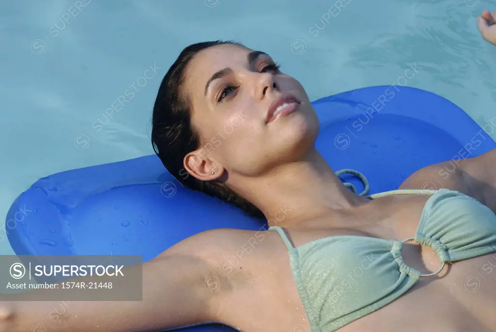Close-up of a young woman lying on a pool raft in a swimming pool