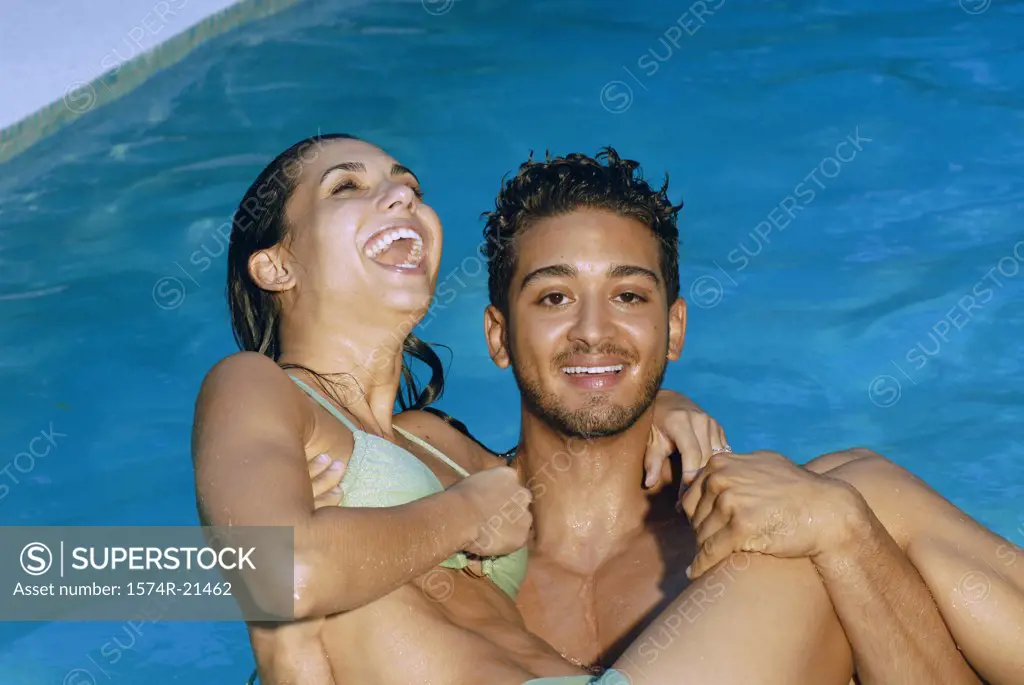 Portrait of a young man carrying a young woman in a swimming pool